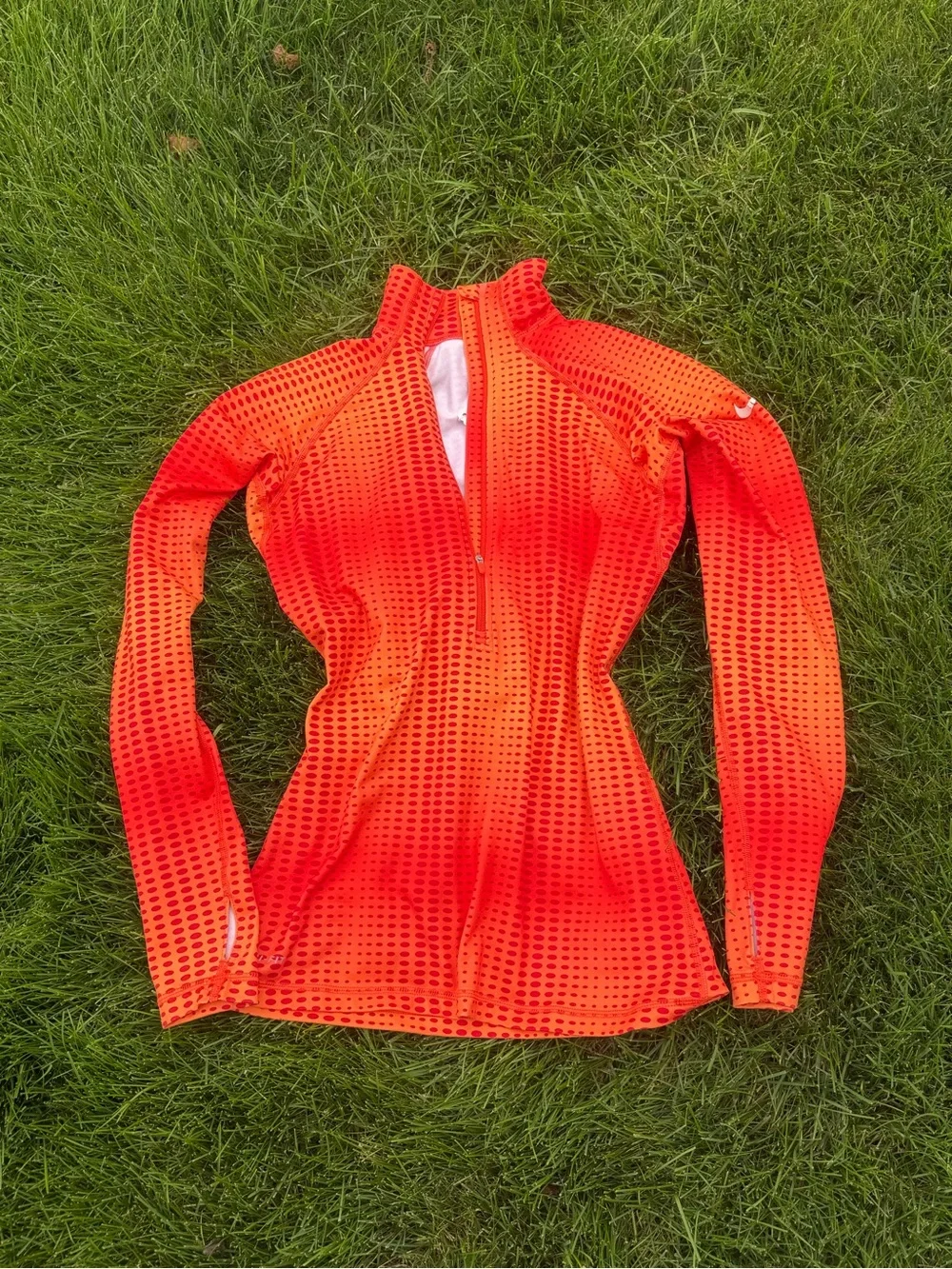 The Nike Pro Hyperwarm half-zip running top features a vibrant orange and red